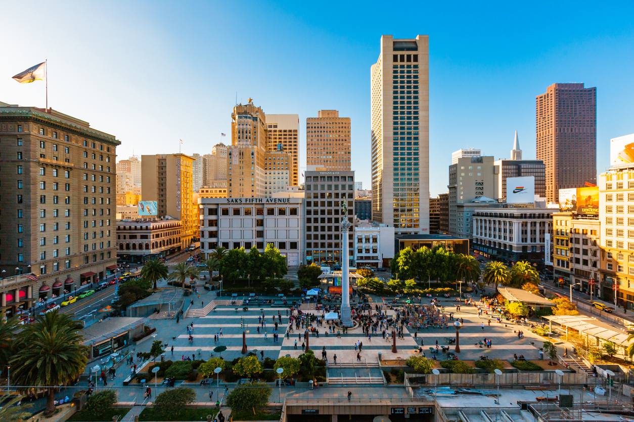 sf dental associates caroline le dentist union square | San Francisco Dental Associates Aerial view of a busy city plaza with a tall central monument, palm trees, and surrounding high-rise buildings filled with pedestrians.